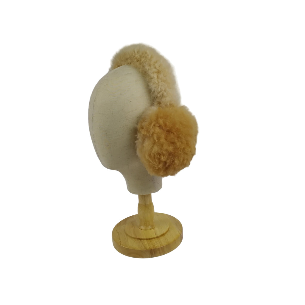 Beige ear muffs on a mannequin head against a plain background