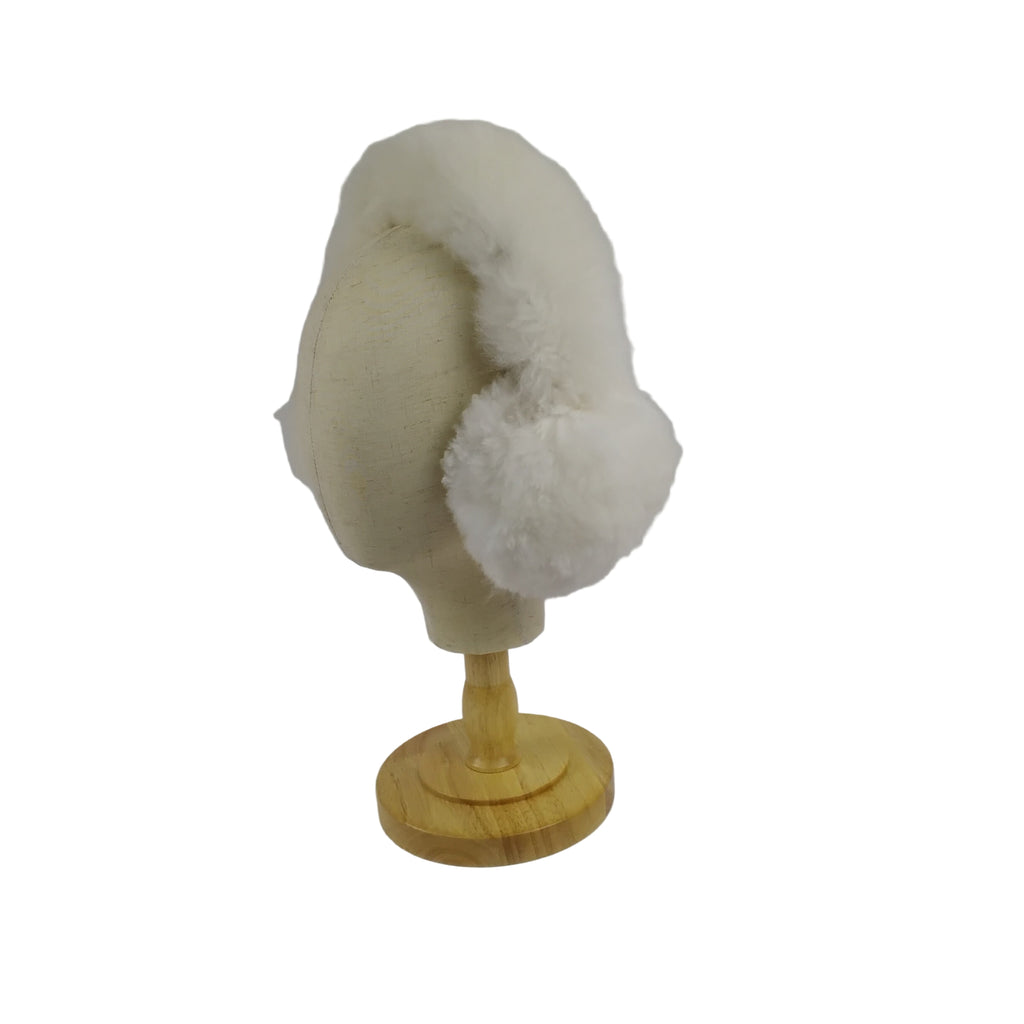 Beige and white fur ear muffs on a wooden mannequin head against a plain background