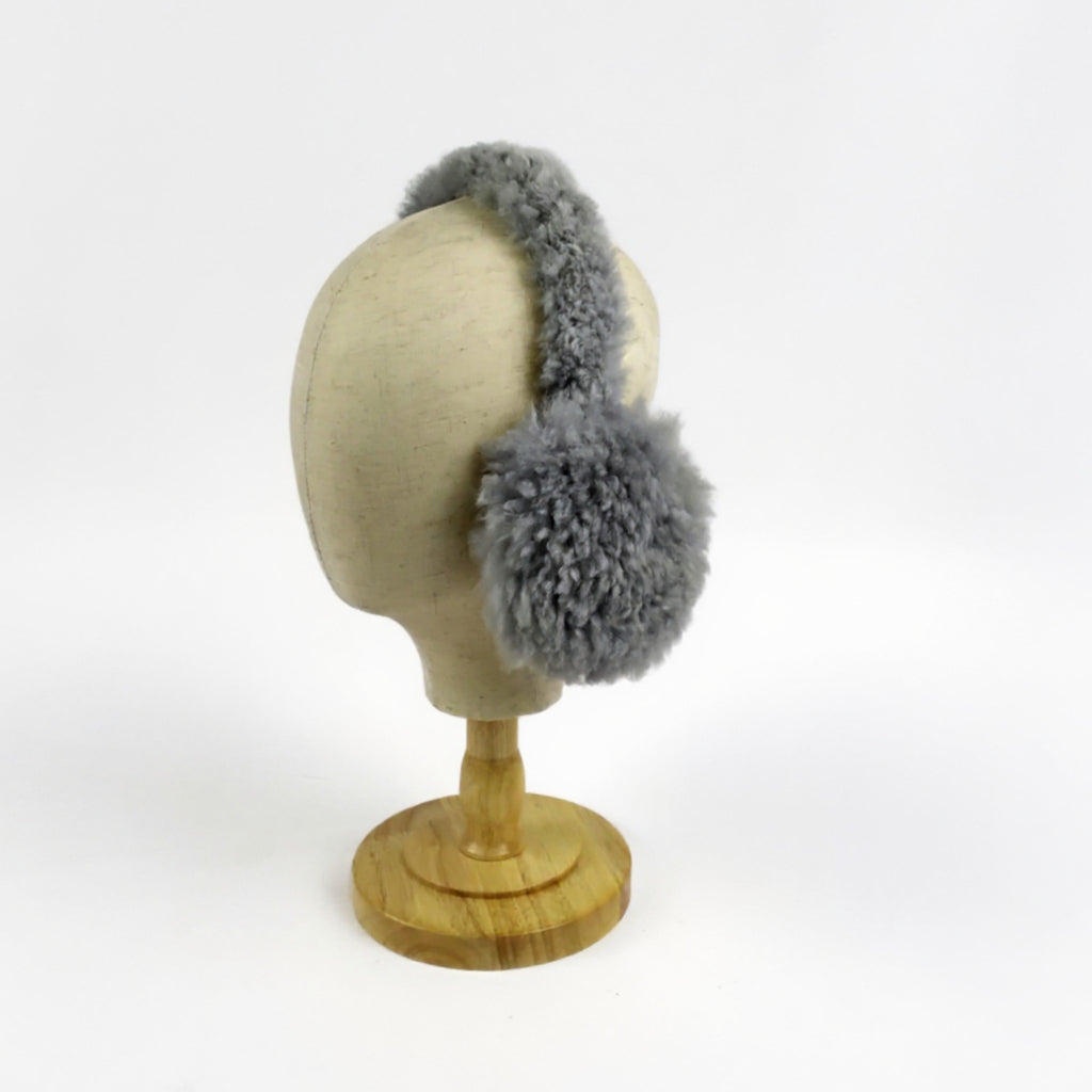 Gray furry ear muffs on a mannequin head against a white background